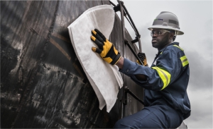 pictured: an EnviroServe worker wearing safety coveralls, gloves, and a hard hat cleans the side of a tank