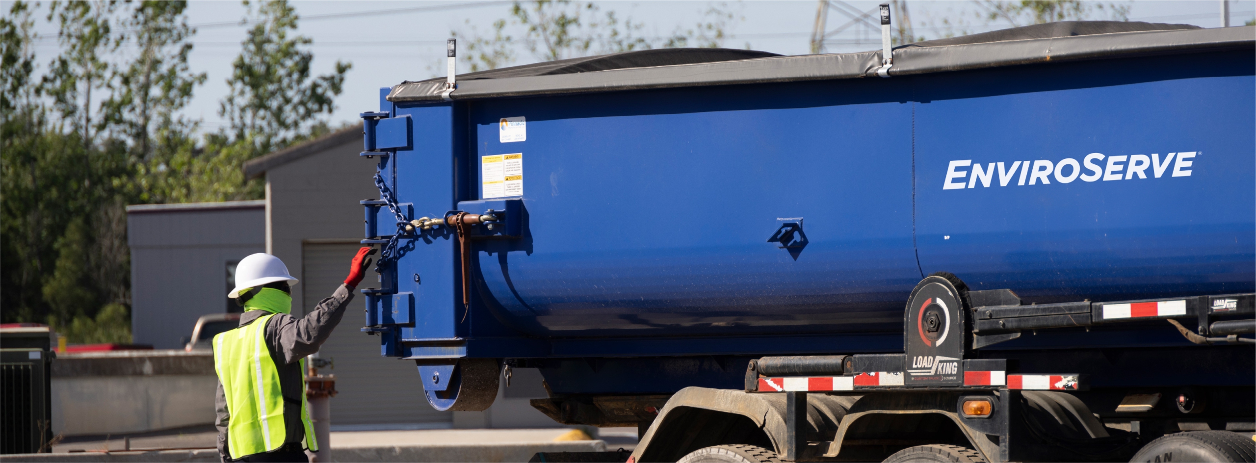 pictured: an EnviroServe worker operates a hose from a large equipment truck