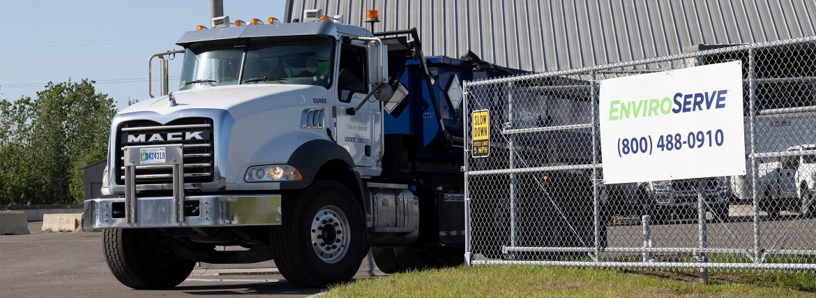 pictured: an EnviroServe truck parked outside a facility, next to a chainlink fence | text: ENVIROSERVE (800) 488-0910