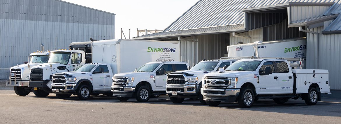 pictured: a small fleet of EnviroServe trucks parked outside a hazardous waste management facility