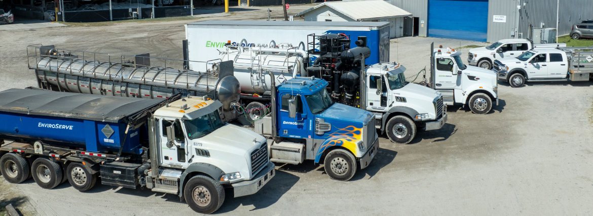 pictured: aerial view of three EnviroServe waste management trucks including a semi truck painted with yellow flames on a blue cab