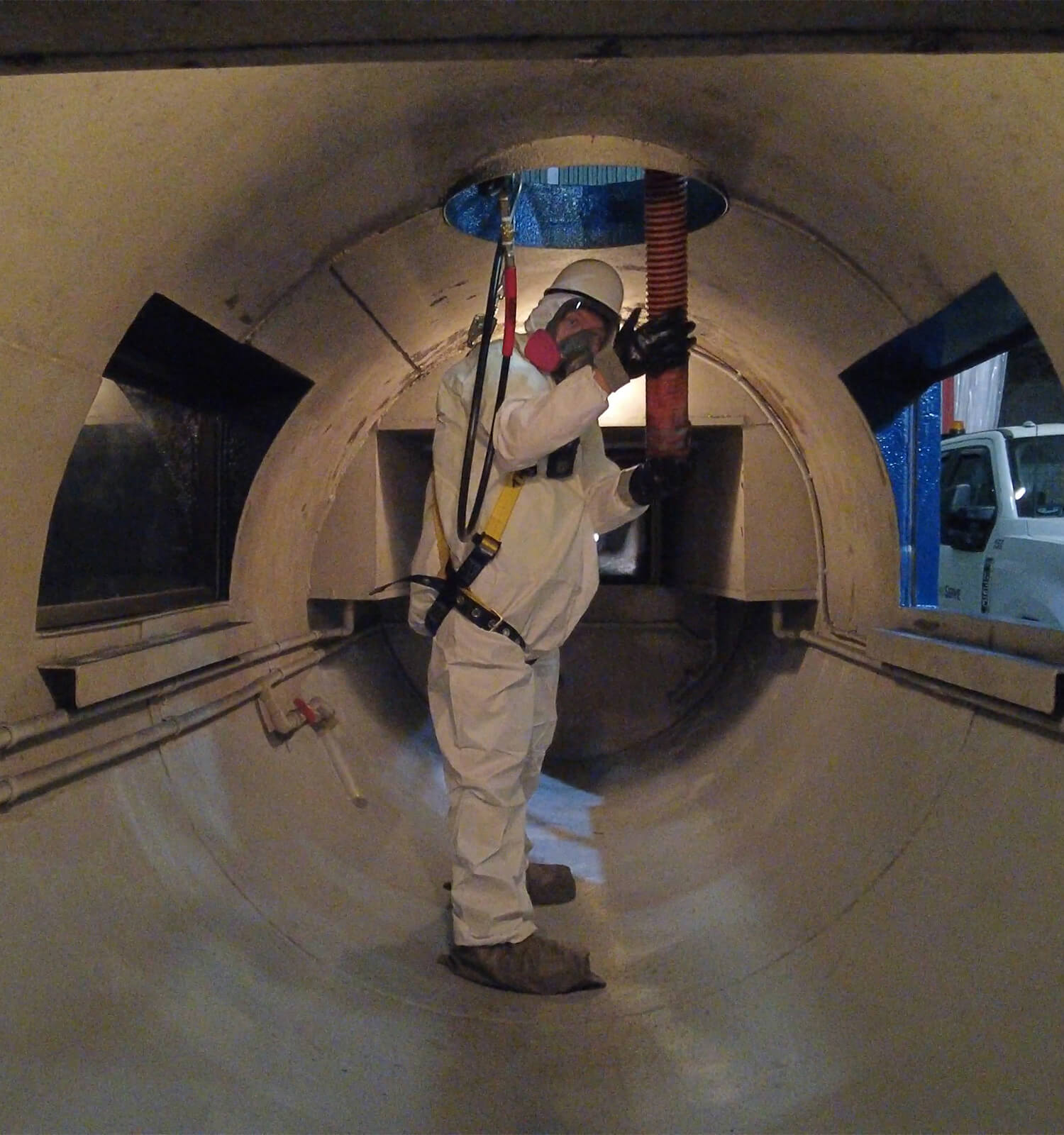 pictured: an EnviroServe worker operates a hose from within a large main